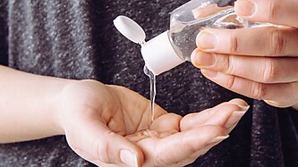 A person squeezes hand sanitizer into their hands